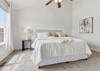 Bright and airy bedroom featuring large window, vaulted ceiling, neutral tones, and a comfortable layout for relaxation.