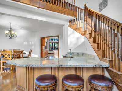Functional wet bar with granite countertops, seating area, and custom wood finishes perfect for hosting guests. Conveniently located near the dining room and staircase, this space enhances the home's entertainer-friendly layout.