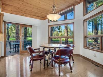 Cozy breakfast area featuring panoramic golf course views, vaulted wood ceilings, and access to the outdoor deck. This light-filled dining space creates the perfect place to enjoy quiet mornings surrounded by Flagstaff pines.