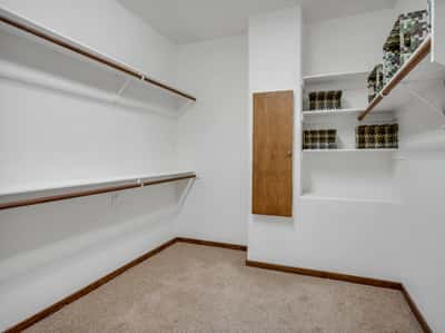 Generously sized walk-in closet with built-in shelving, dual hanging areas, and organized storage space. This functional luxury feature enhances convenience and organization within the spacious primary suite.