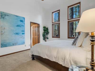 Charming guest suite with oversized windows, high ceilings, and beautiful natural light throughout. Surrounded by towering pines, this bedroom captures the peaceful atmosphere of luxury mountain living in Flagstaff.