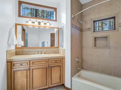 Guest bathroom with tiled shower surround, custom vanity cabinetry, and updated lighting fixtures. Neutral finishes and thoughtful design create a comfortable and stylish space for residents and visitors alike.