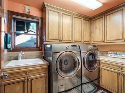 Spacious laundry room with abundant cabinetry, utility sink, counter workspace, and upgraded appliances. Thoughtfully designed storage and organization features enhance convenience throughout the home.