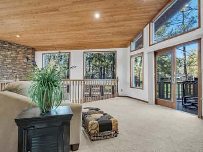 Open loft living area with soaring wood ceilings, oversized windows, and beautiful views of the 12th fairway. This versatile retreat provides additional lounge space filled with natural light and mountain charm.