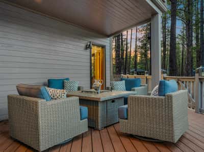 Covered outdoor lounge area with comfortable seating, wood decking, and peaceful forest surroundings. This inviting patio space provides year-round enjoyment and effortless indoor-outdoor living.