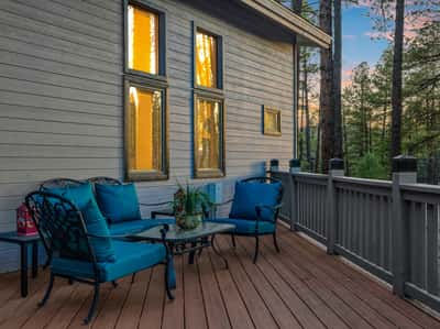 Elevated deck retreat with stylish outdoor seating, wooded surroundings, and tranquil sunset views. This private outdoor space offers a relaxing setting for enjoying the beauty of Flagstaff.