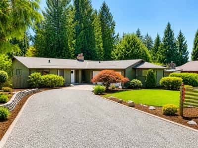 Spacious single-story home situated on a tranquil lot surrounded by lush greenery.