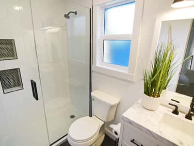Modern bathroom featuring a sleek glass shower, fresh design elements, and ample natural light.