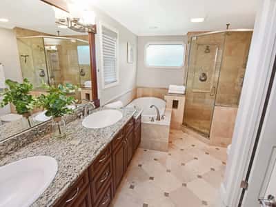 This sophisticated bathroom features modern amenities, dual vanities, a spacious shower, and a relaxing tub area.