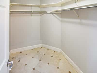 Spacious walk-in closet featuring tile flooring and ample hanging storage for organized living.