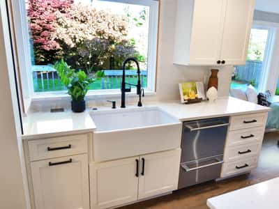 Bright kitchen featuring a farmhouse sink, modern fixtures, and abundant natural light with garden views.
