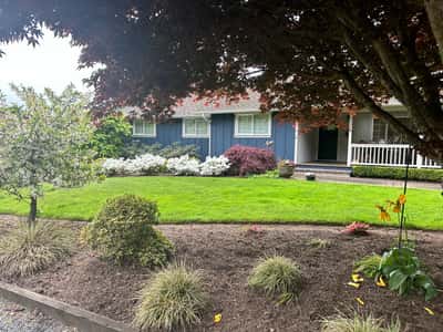 Spacious home surrounded by vibrant landscaping and mature trees, offering a welcoming atmosphere and ample outdoor space.