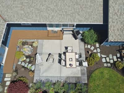 Spacious outdoor patio with dining area, surrounded by lush landscaping and thoughtful stone pathways.