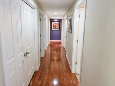 Spacious hallway featuring gleaming hardwood floors and abundant natural light, connecting multiple rooms for easy access.