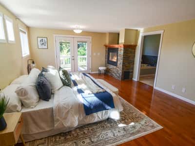 Bright bedroom featuring a cozy fireplace, access to a private balcony, and ample natural light.