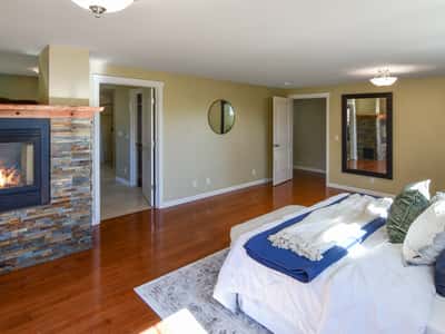 Spacious bedroom featuring a cozy fireplace, modern finishes, and convenient access to adjoining rooms.