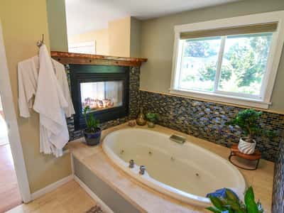 Relax in this inviting bathroom featuring a cozy fireplace and a spacious soaking tub.