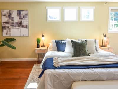 Bright bedroom featuring large windows, modern artwork, and comfortable bedding, perfect for relaxation and comfort.