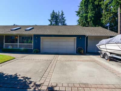 Spacious multi-car driveway leads to a welcoming home with boat storage and mature landscaping.