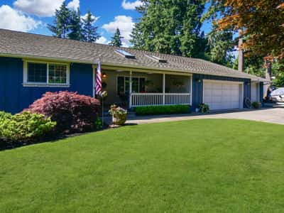 This inviting home features a spacious lawn, well-kept landscaping, and a welcoming porch in a tranquil setting.