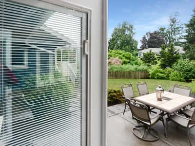 Spacious patio with modern furniture overlooks a lush, well-maintained garden, perfect for outdoor gatherings.