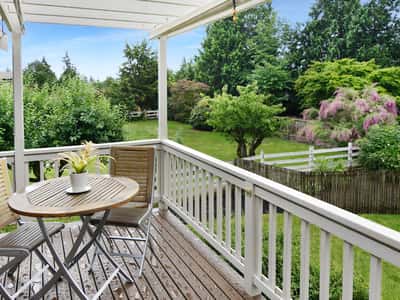 Enjoy al fresco dining on the spacious deck, overlooking a lush, vibrant green landscape and garden.