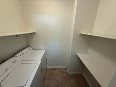 Separate laundry room featuring washer, dryer, built-in shelving, and valuable storage space. This dedicated utility area helps keep the home organized and efficient.
