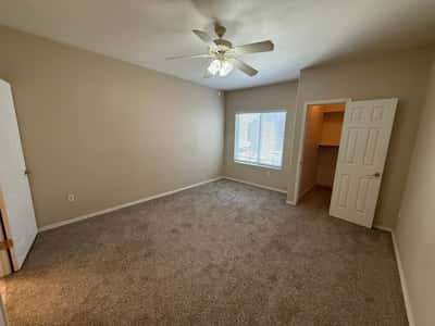 Spacious bedroom with neutral finishes, plush carpeting, ceiling fan, and natural light. A peaceful retreat designed for relaxation and everyday comfort.