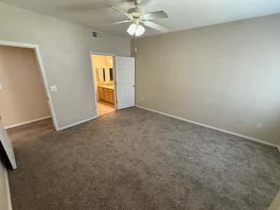 Well-sized bedroom featuring ceiling fan, comfortable carpeting, and convenient access to adjacent living spaces. Ideal for creating a relaxing personal retreat.