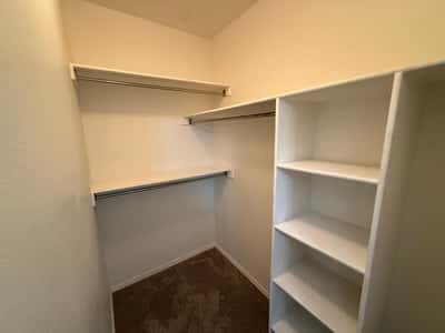 Spacious walk-in closet with built-in shelving and multiple storage options. Designed to maximize organization while providing plenty of room for clothing and accessories.