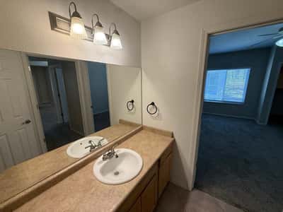 Bright bathroom vanity area featuring modern fixtures, expansive mirror coverage, and generous countertop workspace. This well-maintained Phoenix home offers comfortable living with practical design throughout.