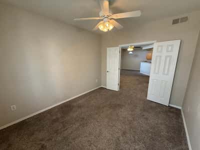 Comfortable secondary bedroom offering soft carpeting, ceiling fan, neutral paint tones, and generous floor space. A versatile addition to this well-maintained Phoenix property.