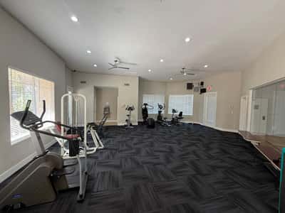 Open fitness center showcasing multiple workout stations, cardio machines, and bright interior spaces. This Phoenix community provides convenient wellness amenities for residents seeking an active lifestyle.