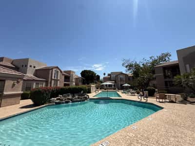 Resort-style pool featuring a decorative waterfall, sun deck, and ample seating areas surrounded by attractive landscaping. Residents of this Phoenix community enjoy exceptional outdoor amenities.
