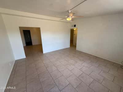Generously sized living room with neutral finishes, ceiling fan, and durable tile flooring throughout. The open design creates a comfortable environment ideal for entertaining or everyday relaxation.