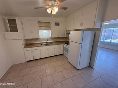 Functional kitchen featuring extensive cabinetry, generous work surfaces, double sink, and included appliances. Ideal for daily cooking, meal prep, and convenient storage organization.