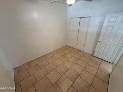 Functional bedroom featuring built-in closet storage, upper cabinets, tile flooring, and a ceiling fan. This efficient space combines comfort with convenient organization options.
