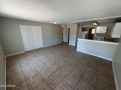 Large open living area with durable tile flooring, neutral color palette, and seamless flow to the kitchen. The versatile layout offers excellent space for entertaining and daily living.