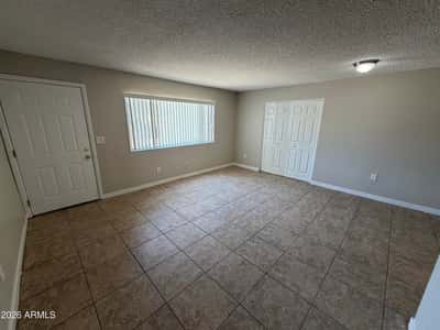 Bright living room with large picture window, neutral paint, and attractive tile flooring. Natural light enhances the welcoming atmosphere throughout the home's central gathering space.