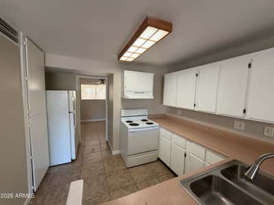 Functional kitchen offering abundant cabinetry, extended countertops, refrigerator, electric range, and practical workspace. Designed for convenience and everyday usability.