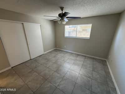 Well-sized bedroom featuring tile flooring, ceiling fan, natural light, and closet storage. A versatile space suitable for guests, family members, or a dedicated workspace.