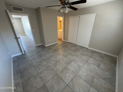 Inviting bedroom with easy-care tile flooring, ceiling fan, spacious closet, and direct bathroom access. Designed to provide comfort, privacy, and everyday functionality.