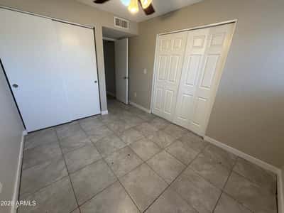 Inviting bedroom with dual closets, tile flooring, ceiling fan, and neutral d cor. Ample storage and a practical layout make this room suitable for guests, family, or a dedicated workspace.