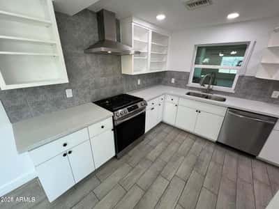 Modern upgrades shine throughout this kitchen, including quartz countertops, stainless appliances, designer backsplash tile, and custom cabinetry. The space is designed for both beauty and everyday convenience.
