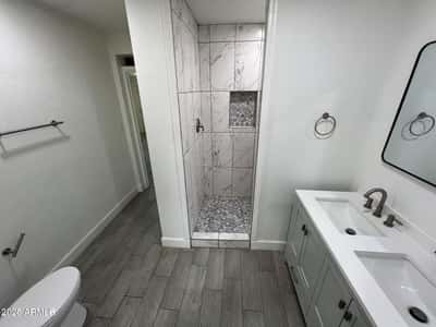 Contemporary finishes define this updated bathroom, highlighted by a spacious walk-in shower, dual vanity, and modern fixtures. The thoughtful design balances comfort and sophistication.