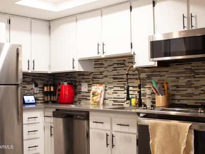 Contemporary finishes shine throughout this remodeled kitchen, highlighted by white cabinetry, stainless appliances, sleek counters, and decorative tile work. The result is a clean and sophisticated cooking space.