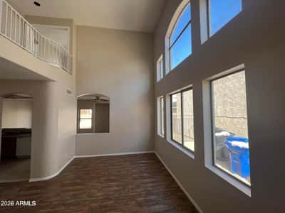 Large picture windows and impressive ceiling heights create a bright and inviting gathering space. This open-concept living area offers flexibility for furniture arrangements and comfortable everyday living.