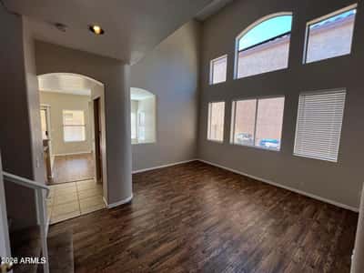Tall ceilings and expansive windows create a bright, airy living space filled with natural light. The open floor plan and stylish flooring make this room perfect for entertaining and everyday comfort.