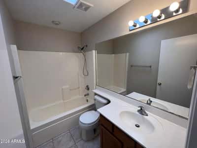 Brightened by a skylight, this full bathroom includes a tub and shower combination, vanity storage, and durable finishes. The clean design complements the home's comfortable layout.