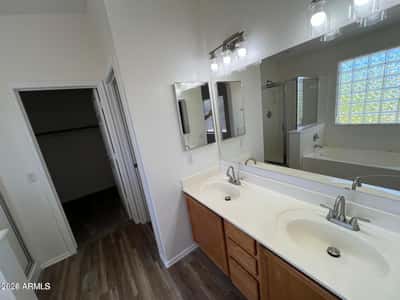 Elegant primary bathroom showcasing dual sinks, expansive counter space, updated fixtures, and a bright open design. The layout offers convenience and comfort for daily routines.
